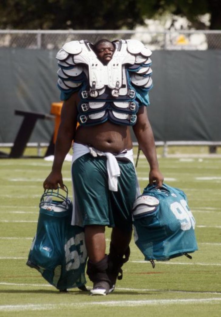 Equipment manager carrying loads of football gear